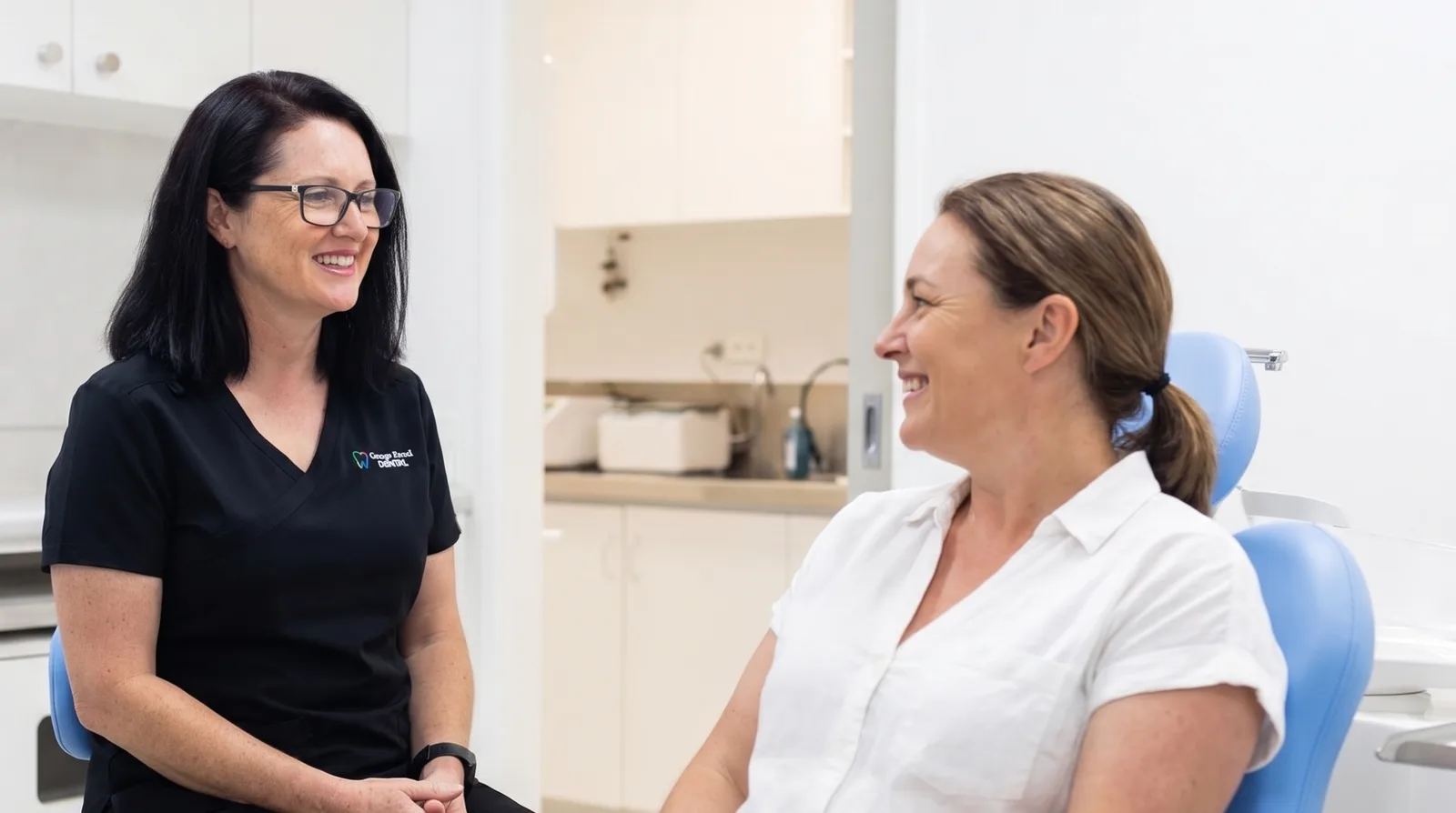 Casey, our Practice Manager and Dental Hygienist, sharing a relaxed chat and a laugh with a smiling patient seated in the dental chair at Grange Road Dental in Ipswich